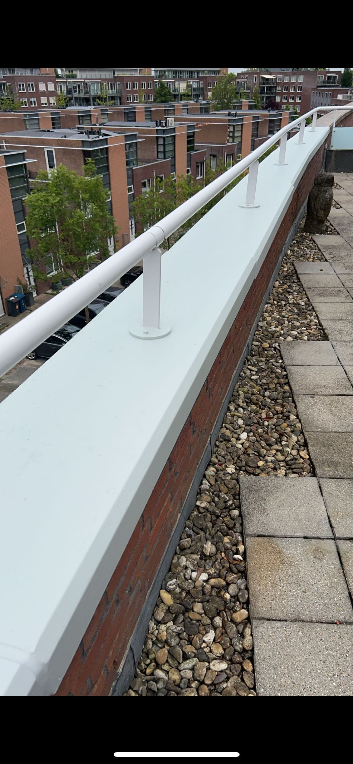 Een witte leuning bovenop een bakstenen gebouw met uitzicht op een stad.
