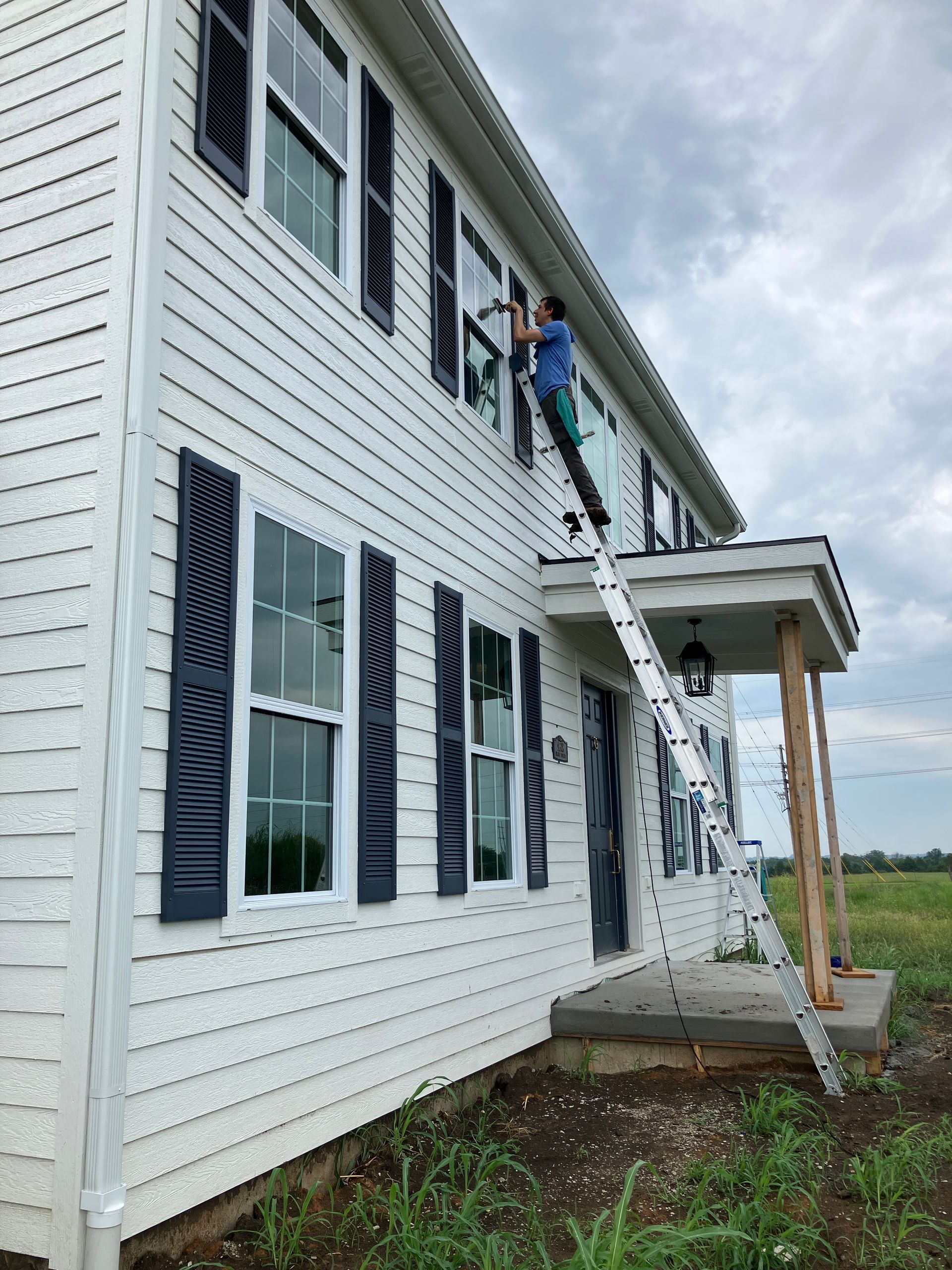 32 foot ladder leaning against new construction build with Brandon from Closing Cleaners cleaning 2nd story windows.