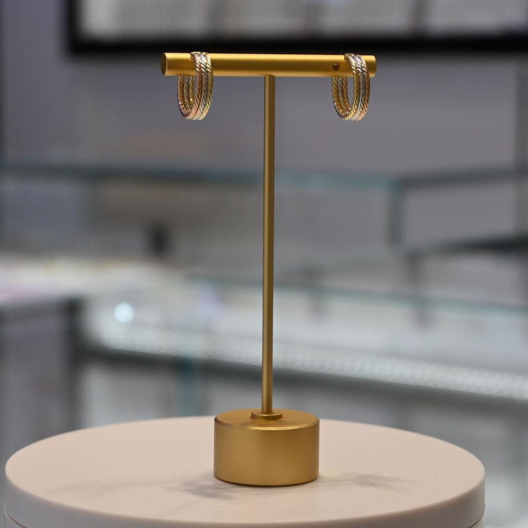 A pair of gold hoop earrings on a gold stand