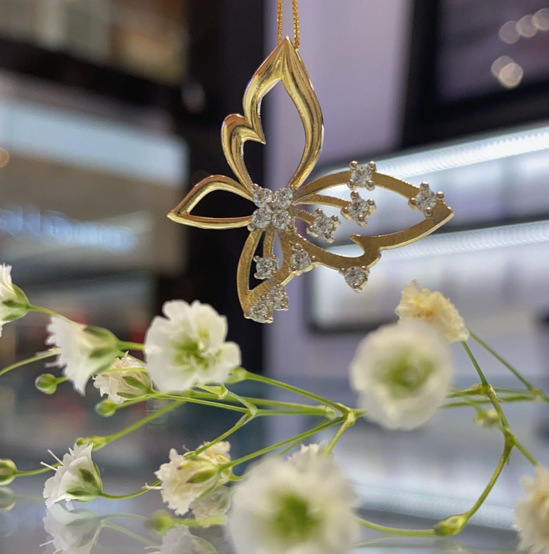 A gold butterfly shaped pendant is hanging from a chain