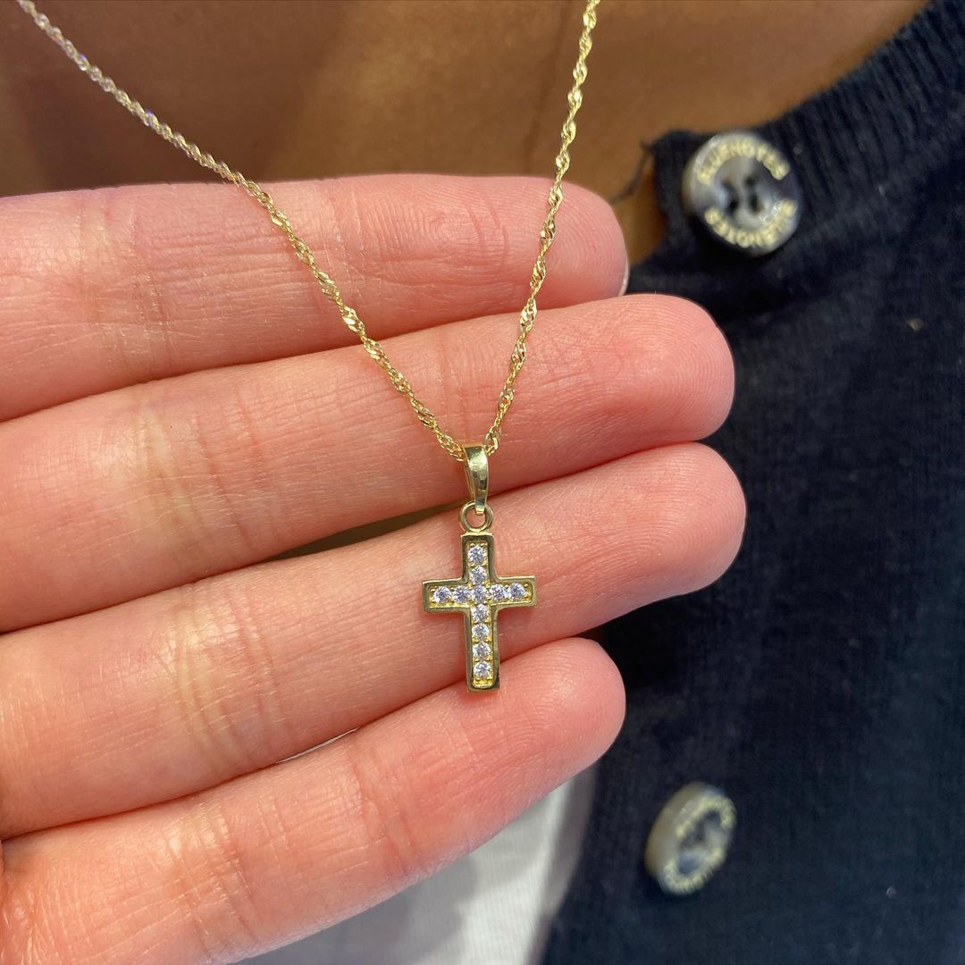 A person is holding a cross necklace in their hand