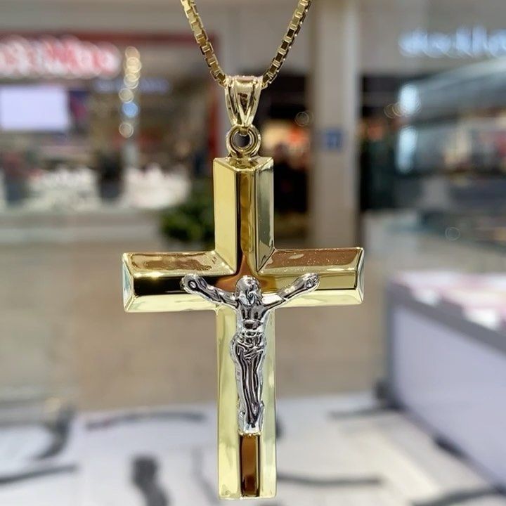 A gold cross with jesus on it is on a chain.