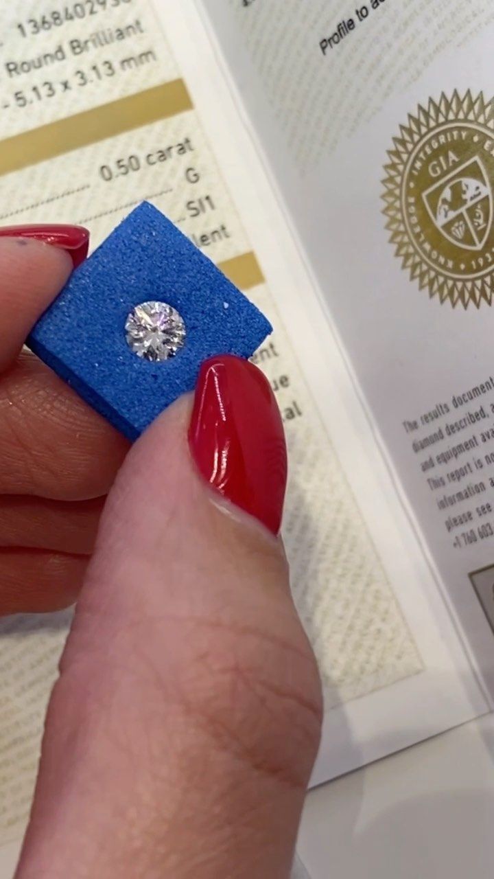 A woman with red nails is holding a diamond in her hand