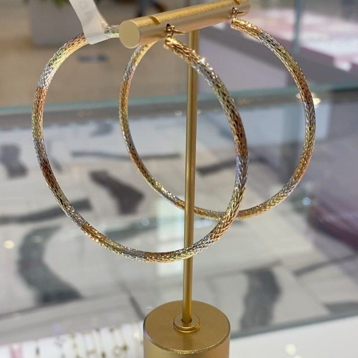 A pair of hoop earrings sitting on top of a gold stand