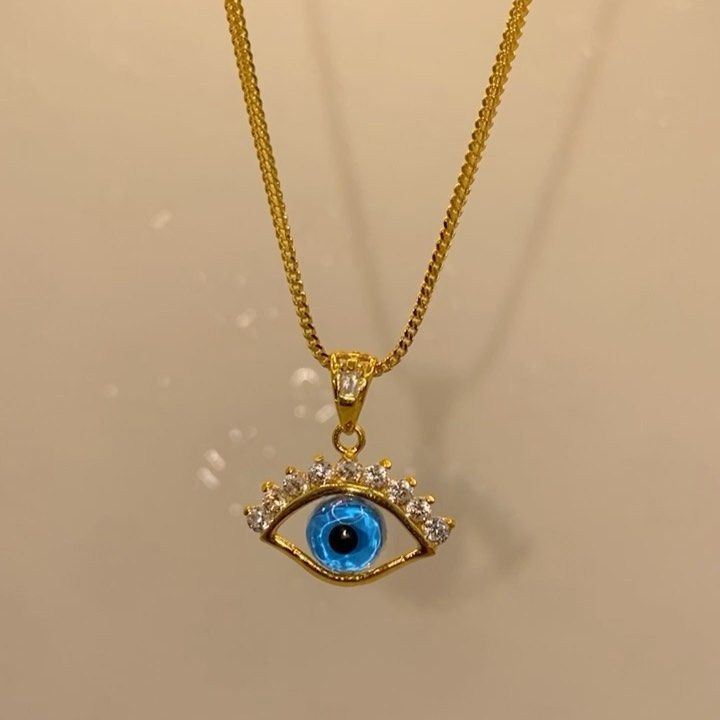 A gold necklace with a blue evil eye pendant