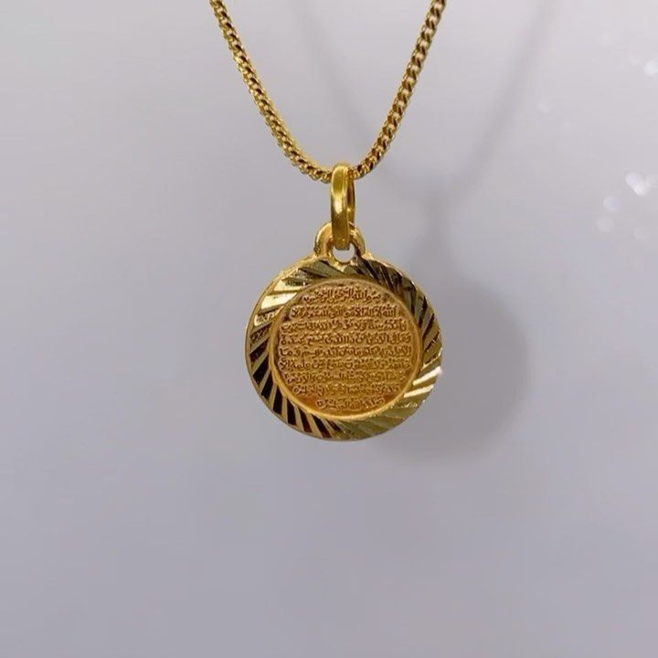 A gold necklace with a round pendant on a chain