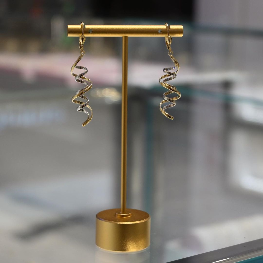 A pair of earrings sitting on top of a gold display stand.