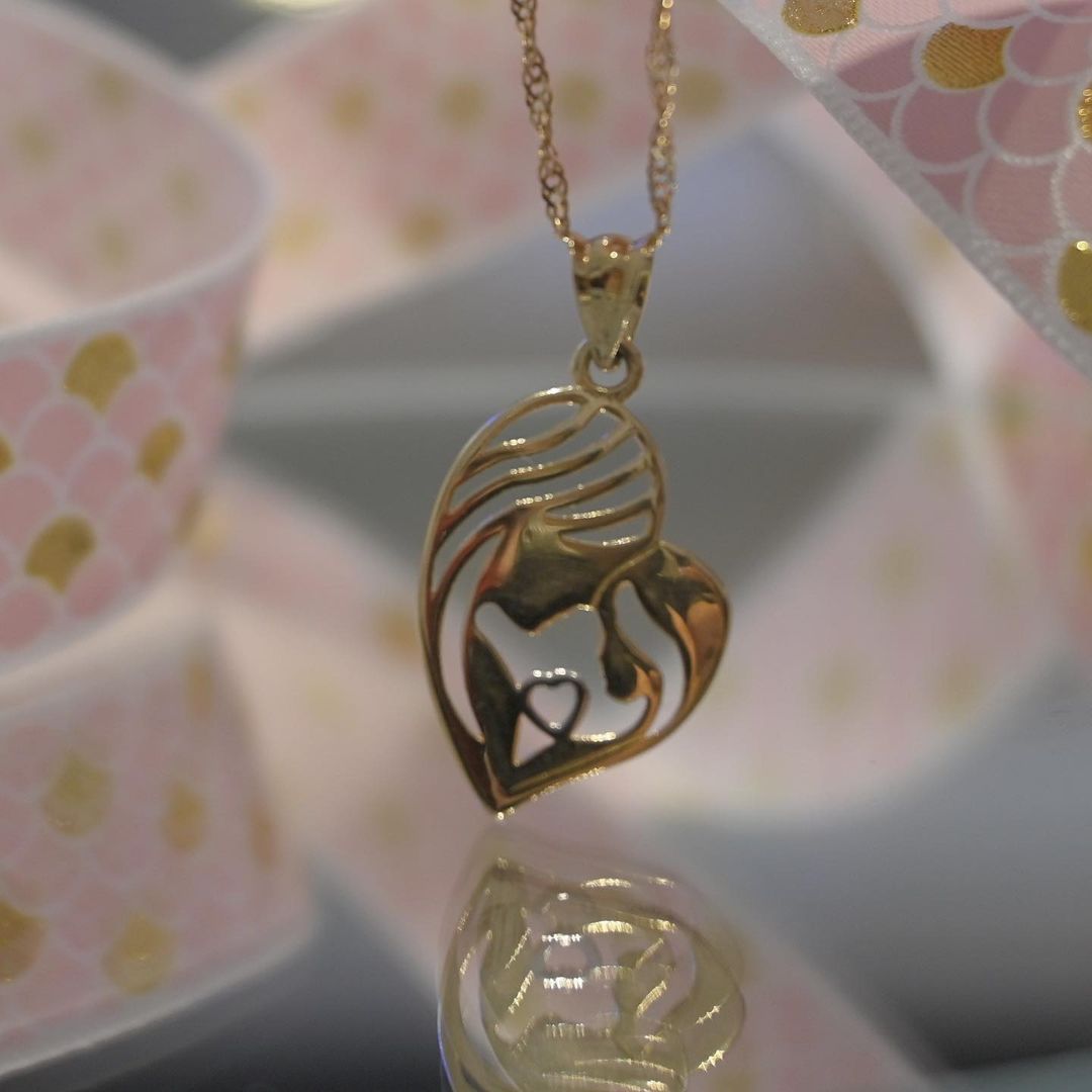 A gold necklace with a heart shaped pendant on a chain