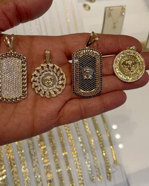 A person is holding four gold pendants in their hand