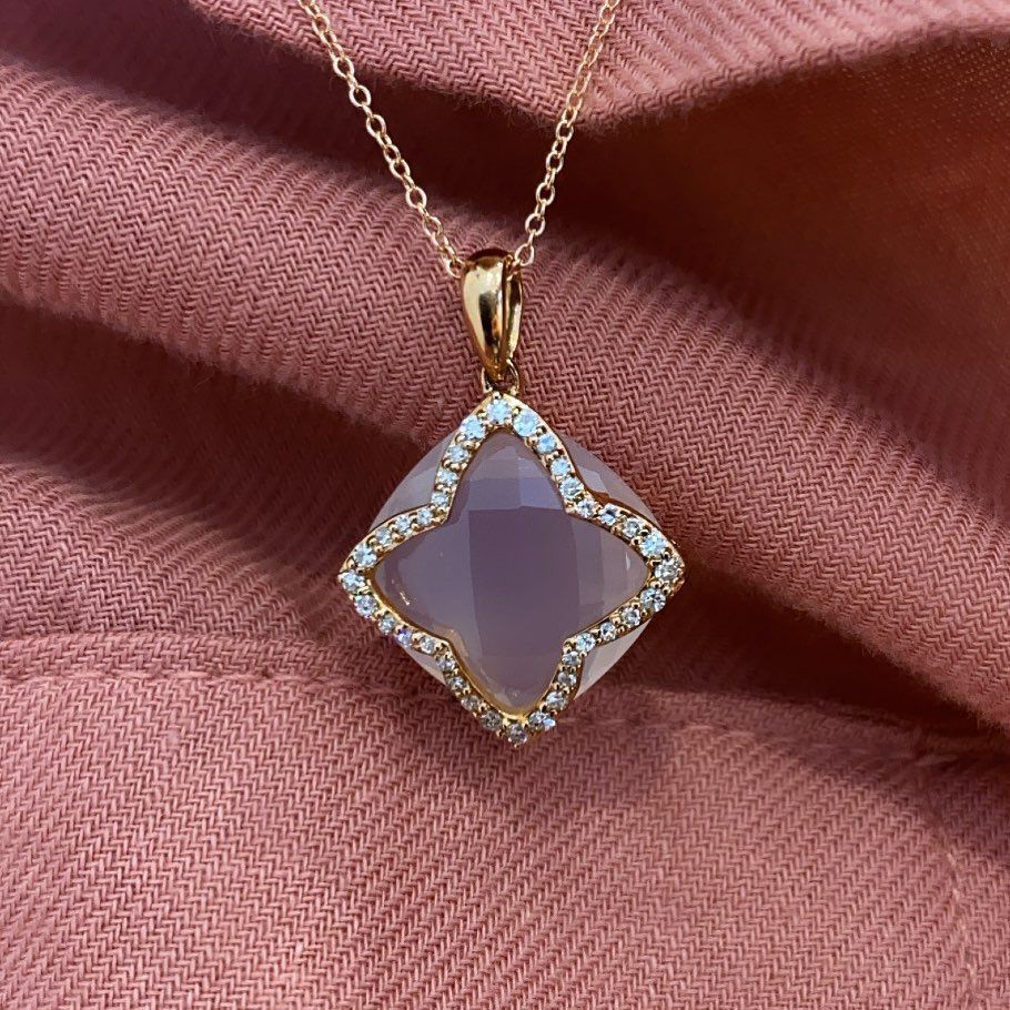A necklace with a square pendant on a pink cloth