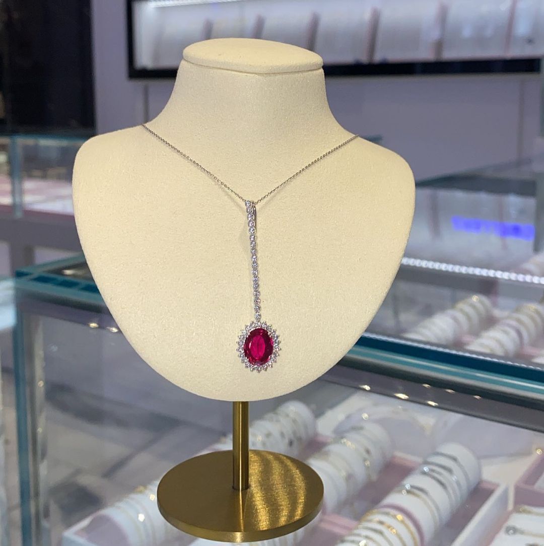 A necklace with a red stone is on a mannequin