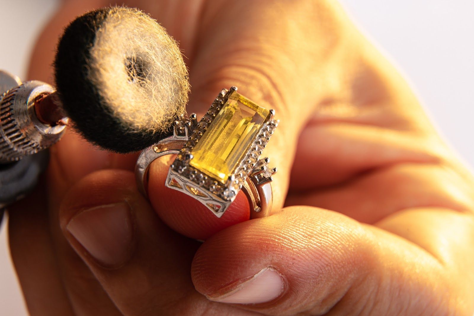 Close-up of a hand holding a tiny circuit board beside a small round brush tool