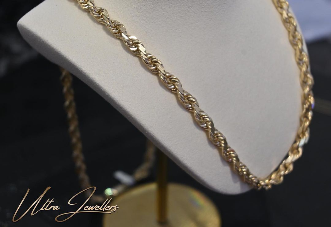 A gold necklace is on a mannequin with the words walter jeweller 's on the bottom