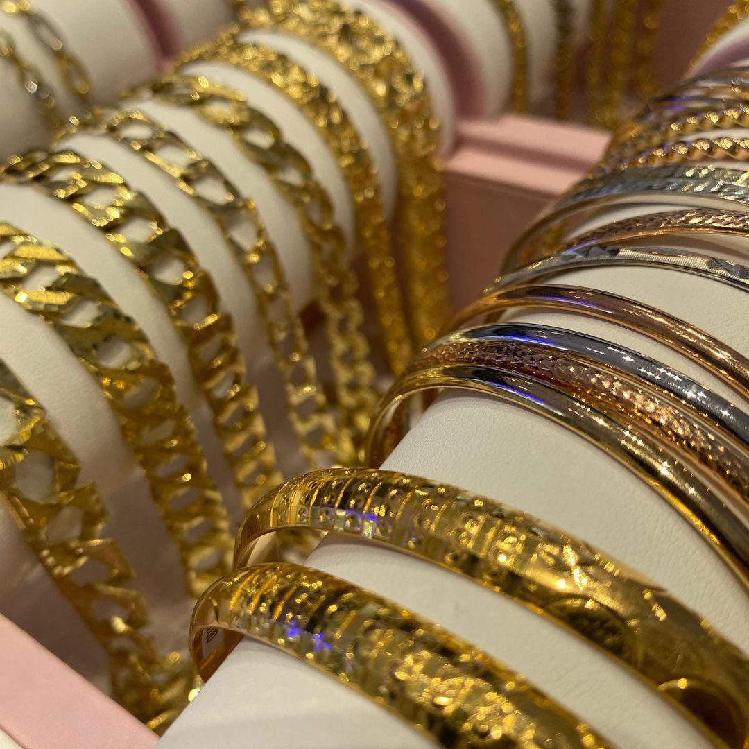 A bunch of gold and silver bracelets are stacked on top of each other
