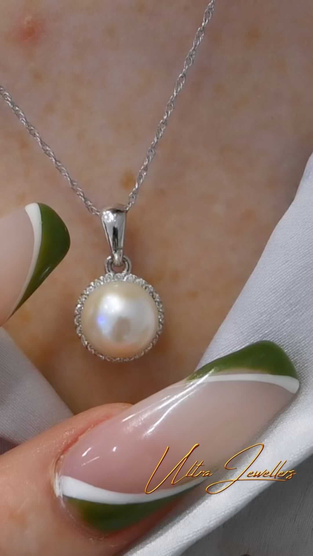 A woman is wearing a necklace with a pearl pendant.