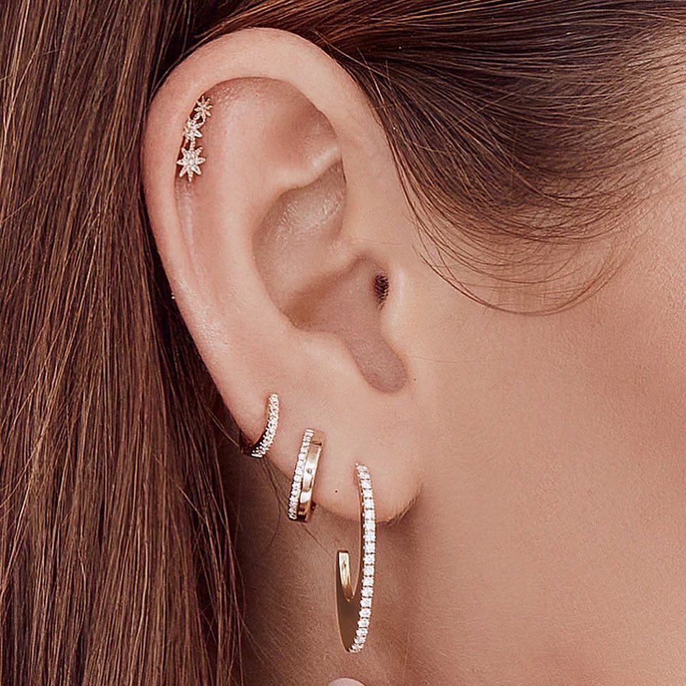 A close up of a woman 's ear with multiple piercings and earrings.