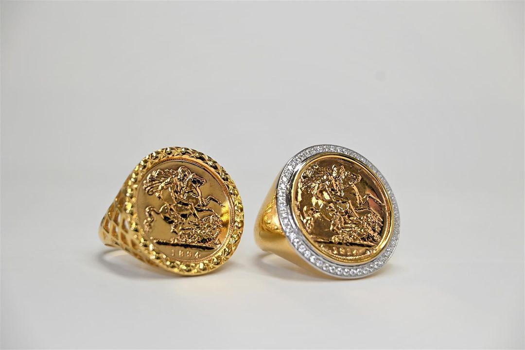 Two gold rings with coins on them are sitting next to each other on a white surface.