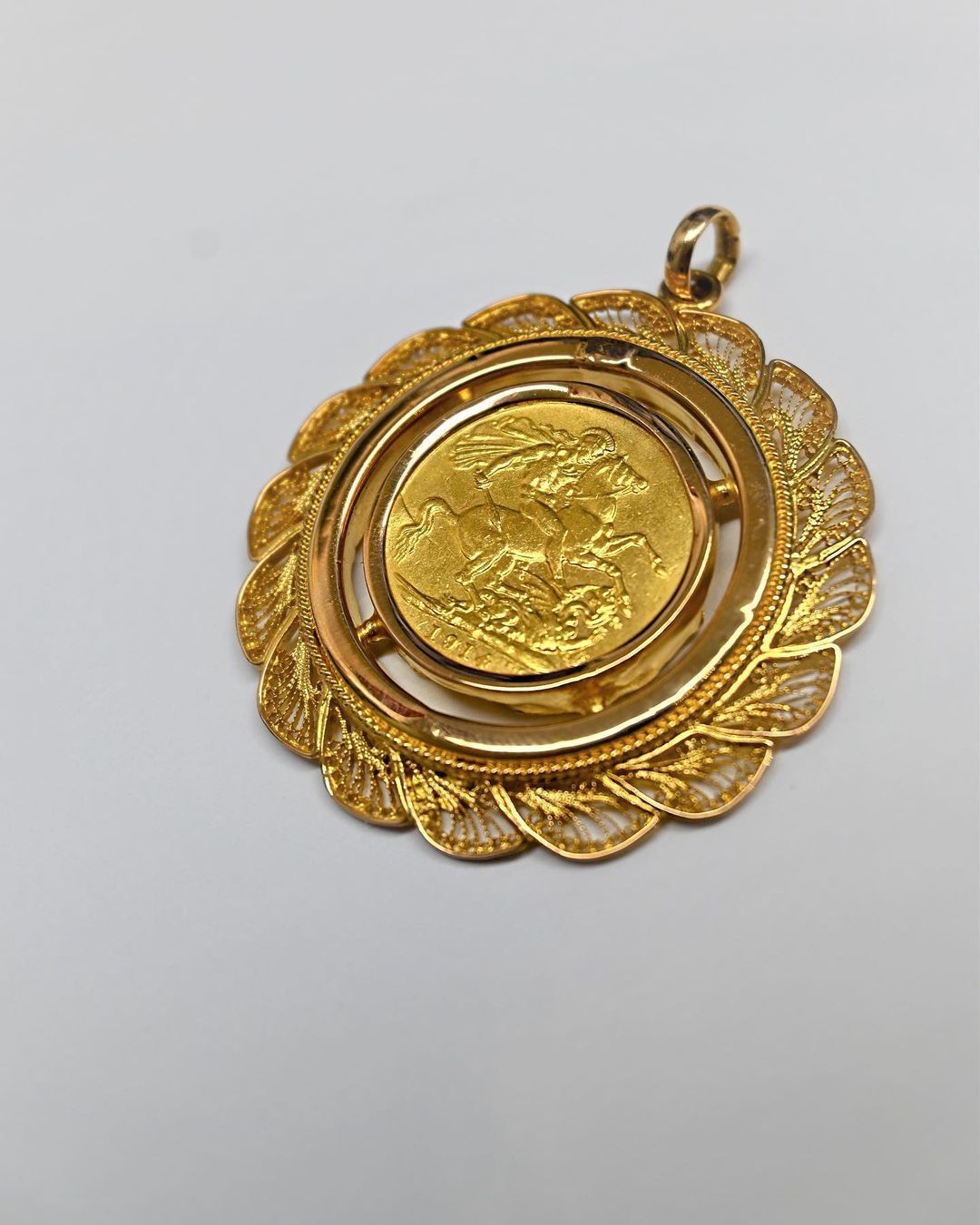 A gold pendant with a coin inside of it