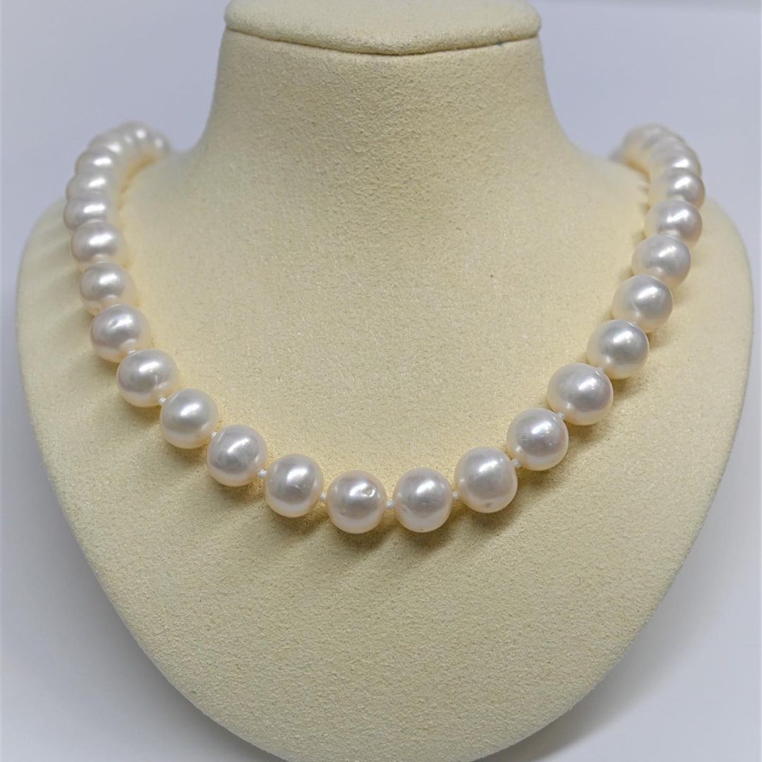 A white pearl necklace is on a mannequin.