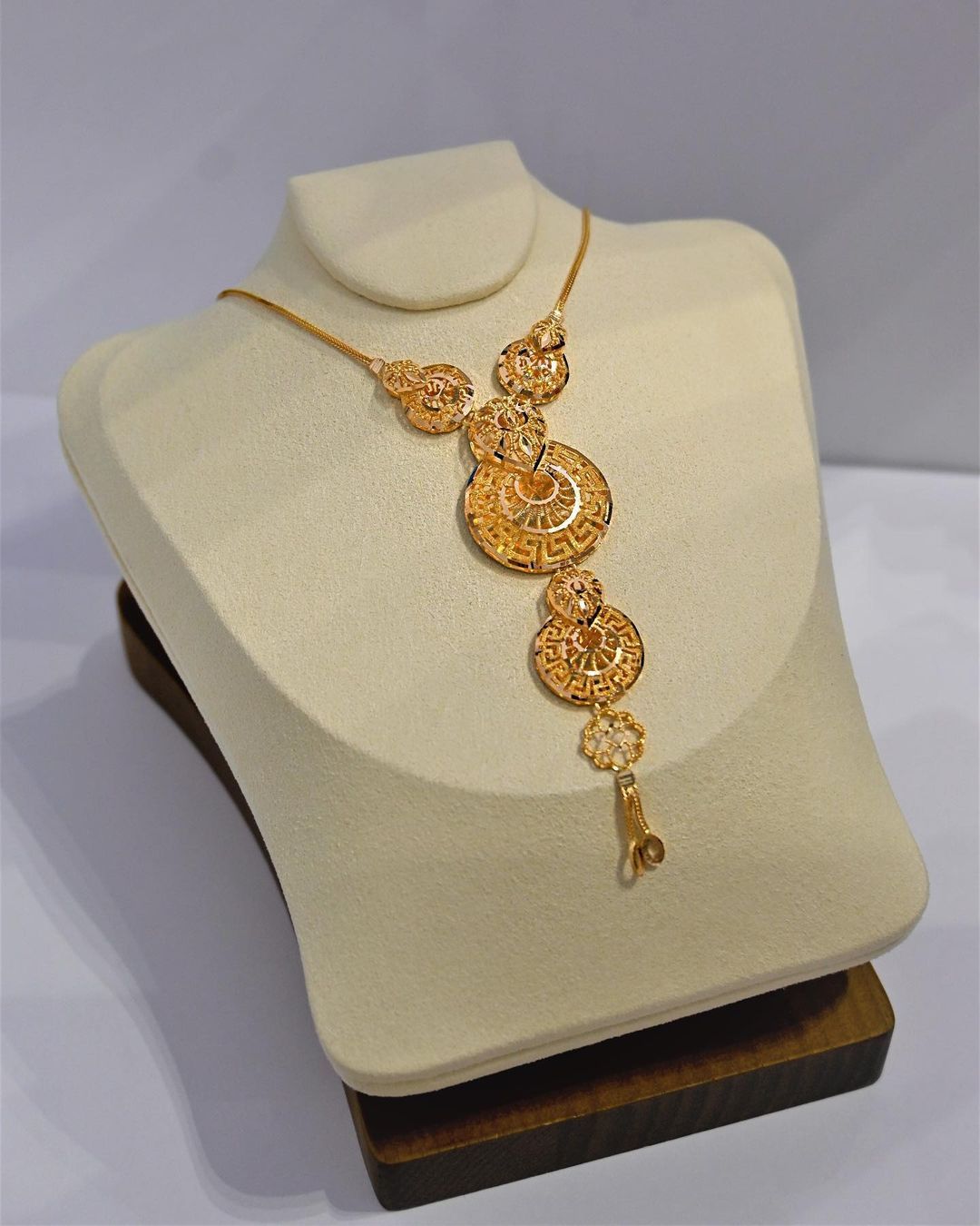 A gold necklace is displayed on a mannequin