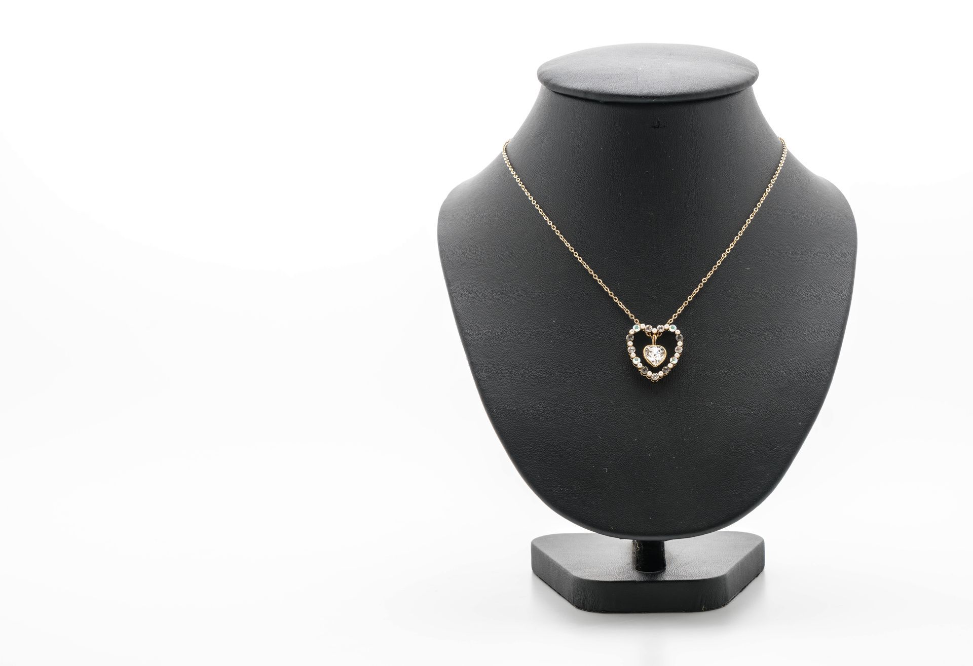 A necklace with a heart shaped pendant is on a mannequin.