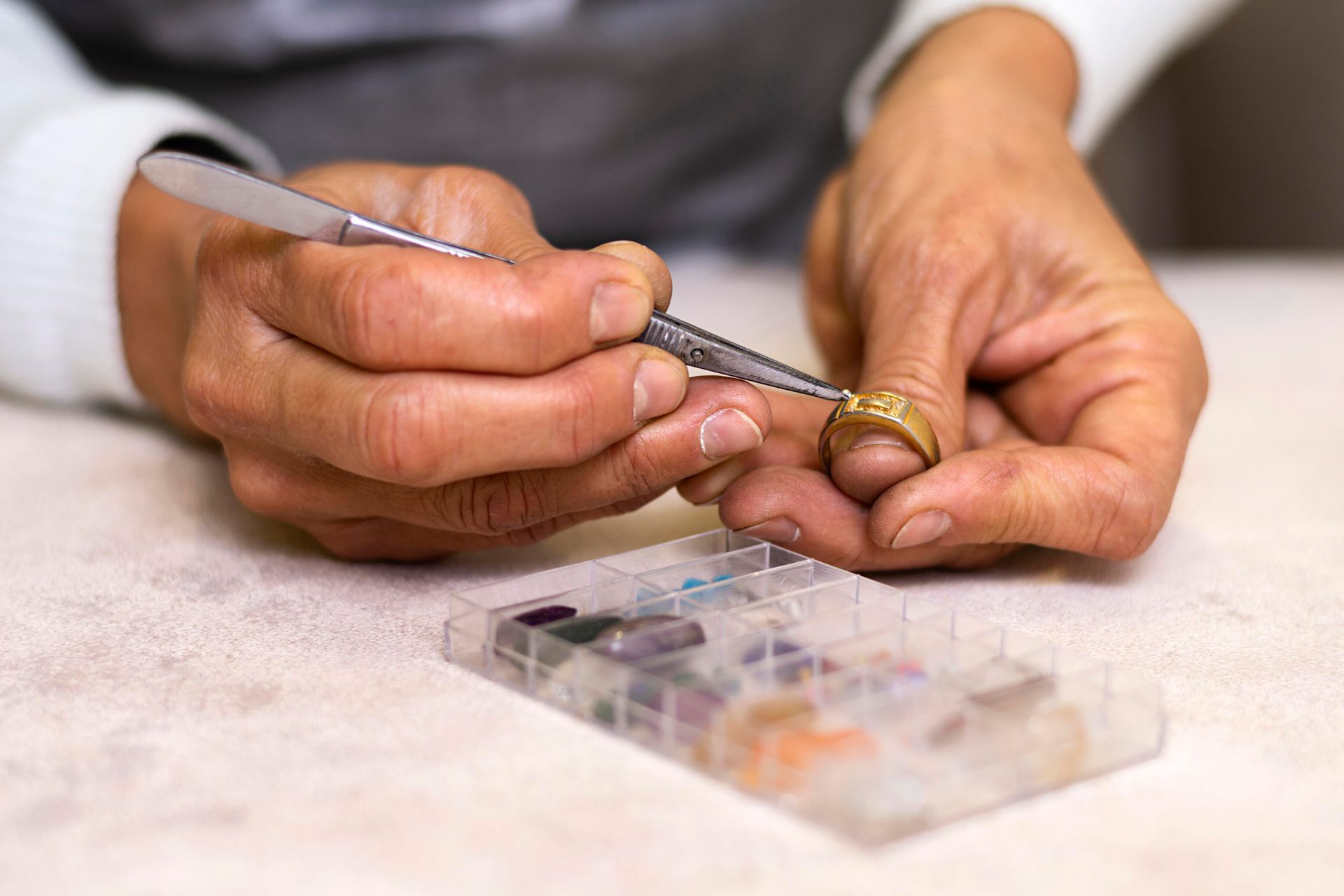 A person is working on a ring with a pair of tweezers.