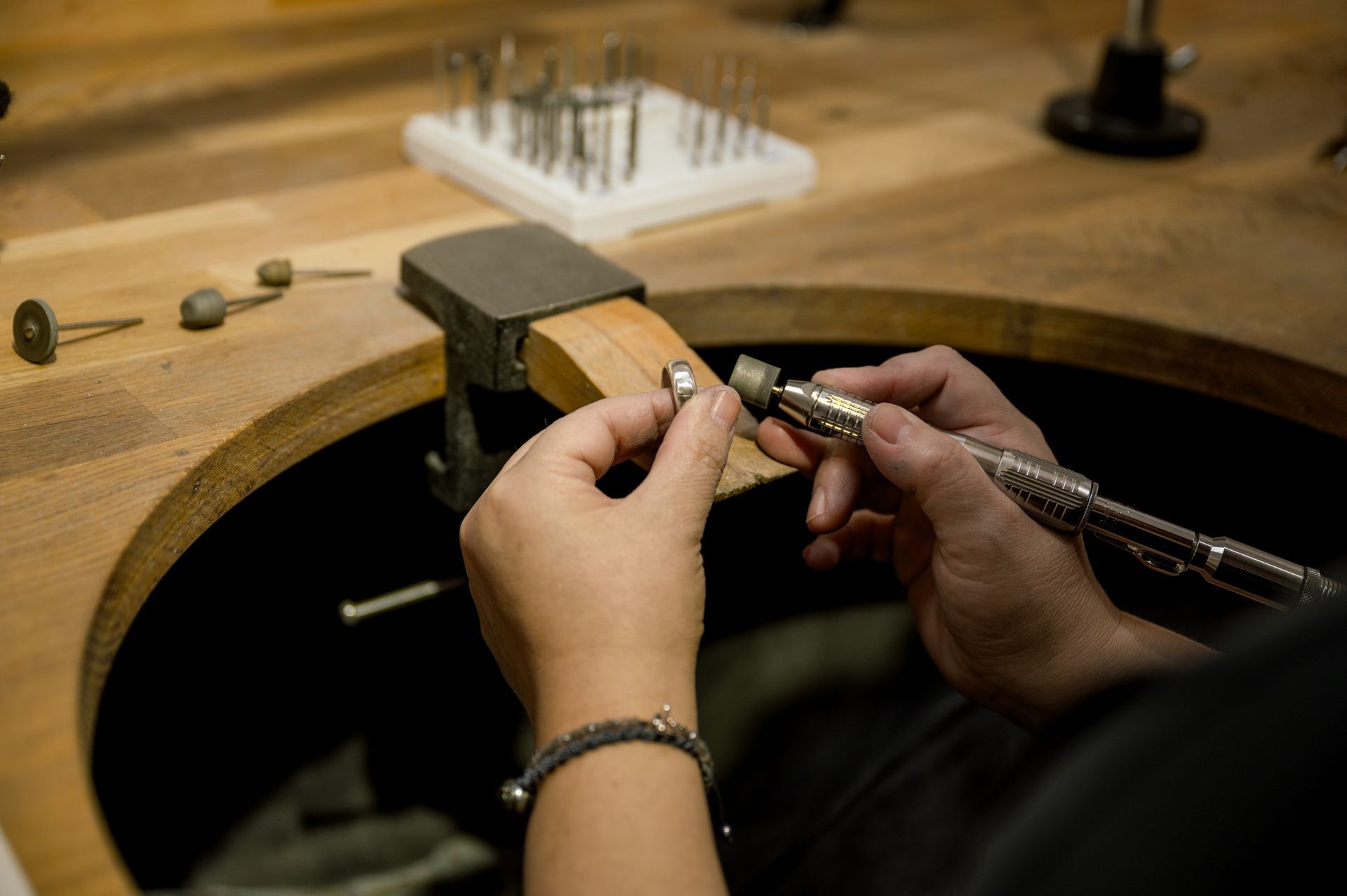 A person is working on a piece of metal on a wooden table.