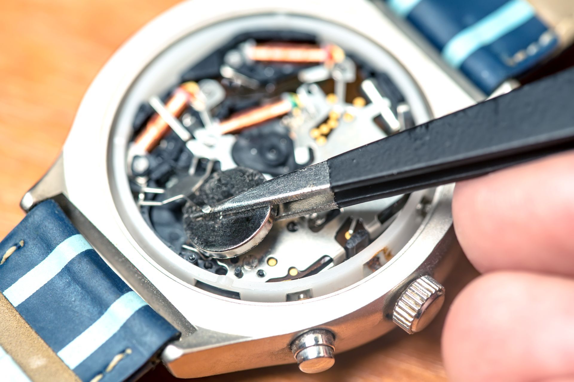 Close-up of a watch being cleaned with a brush on a blue striped strap
