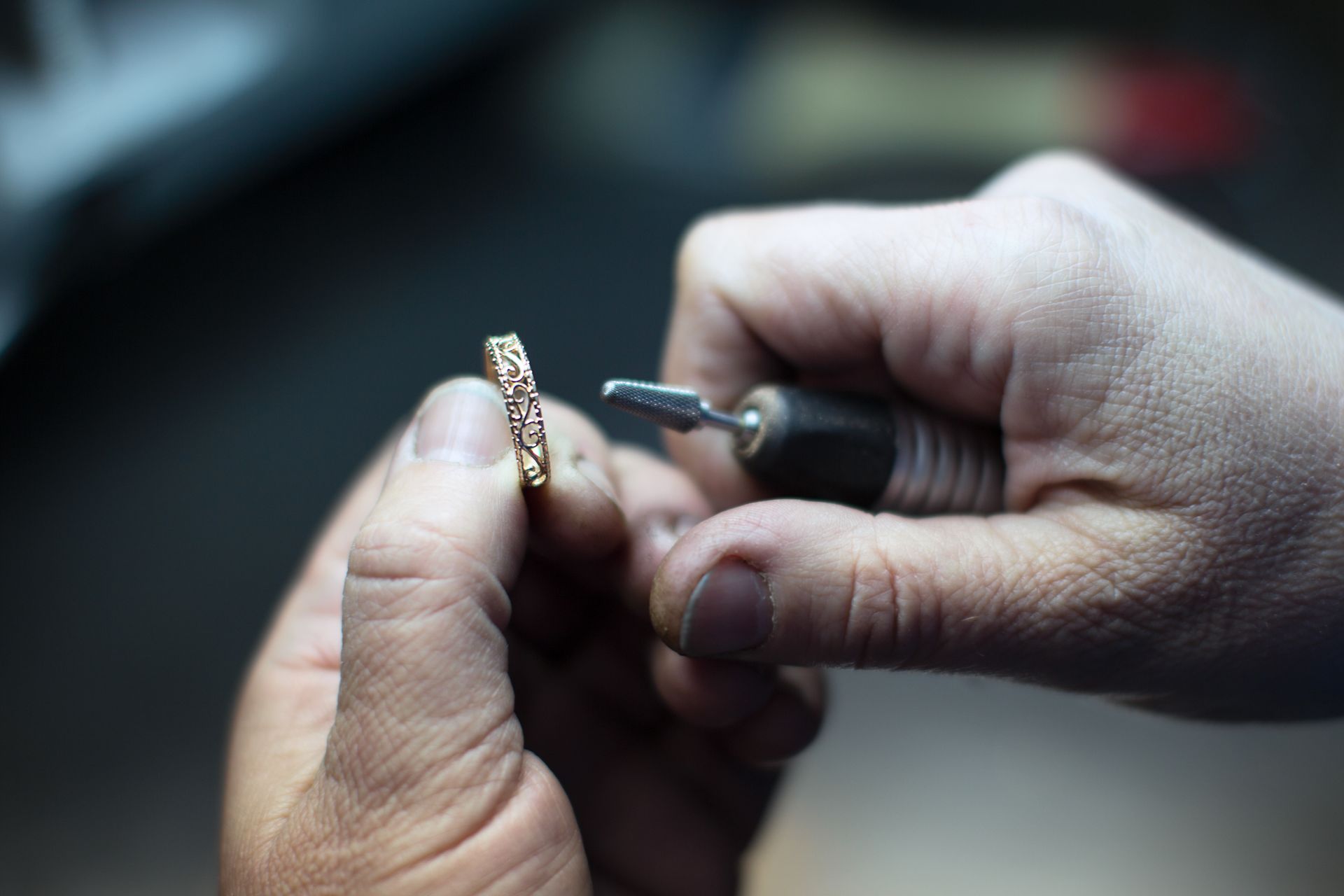 A close up of a person polishing a ring with a tool.
