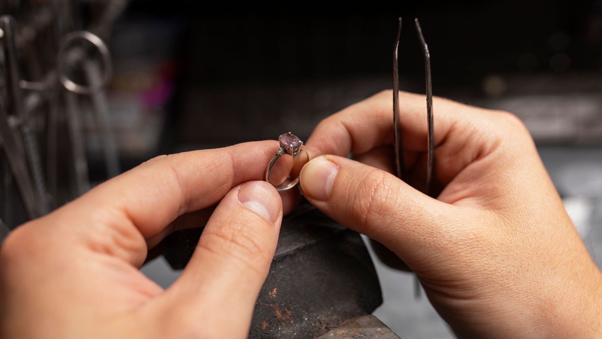 A person is working on a ring with tweezers.