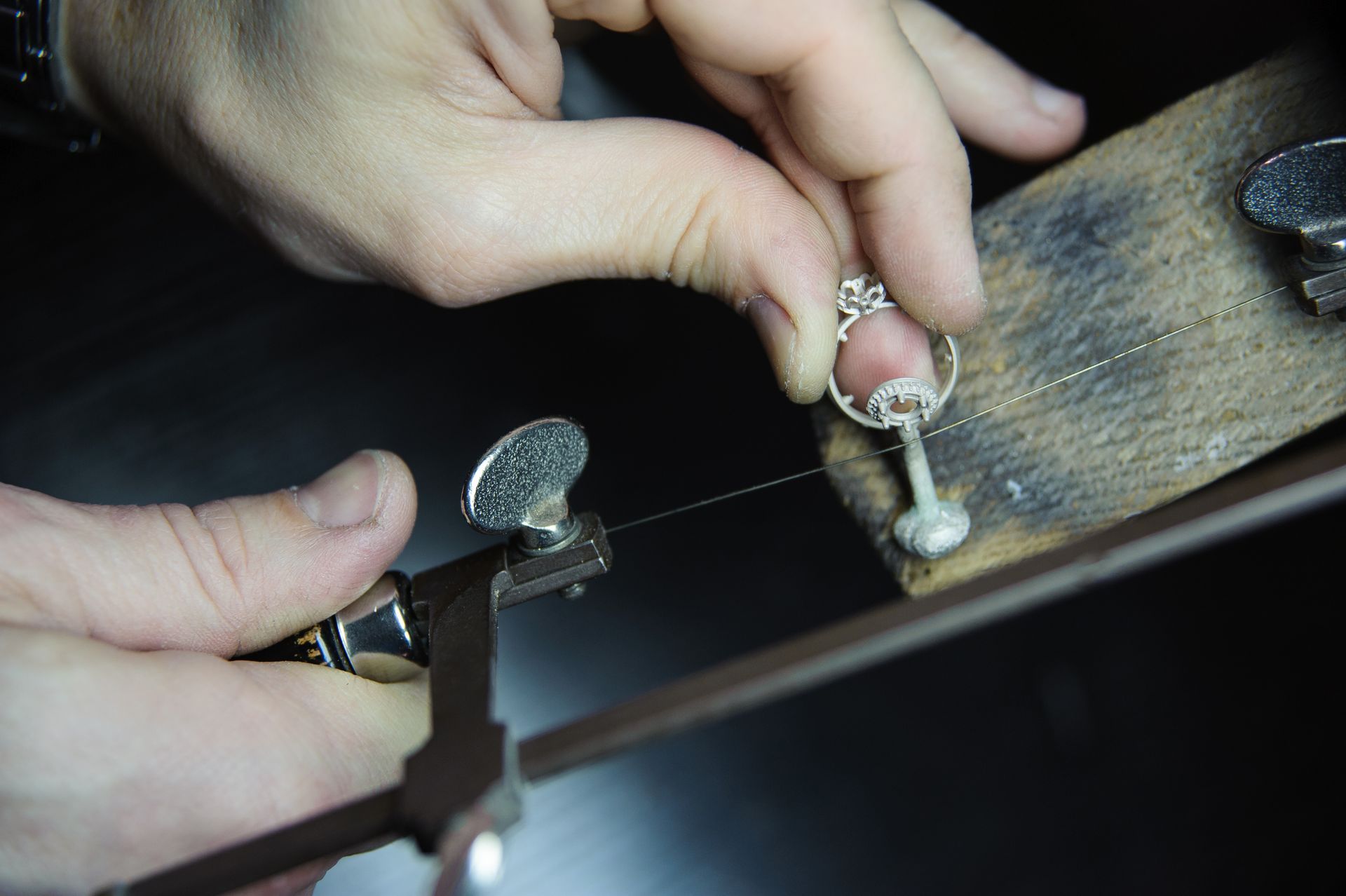 A person is cutting a piece of metal with a saw.