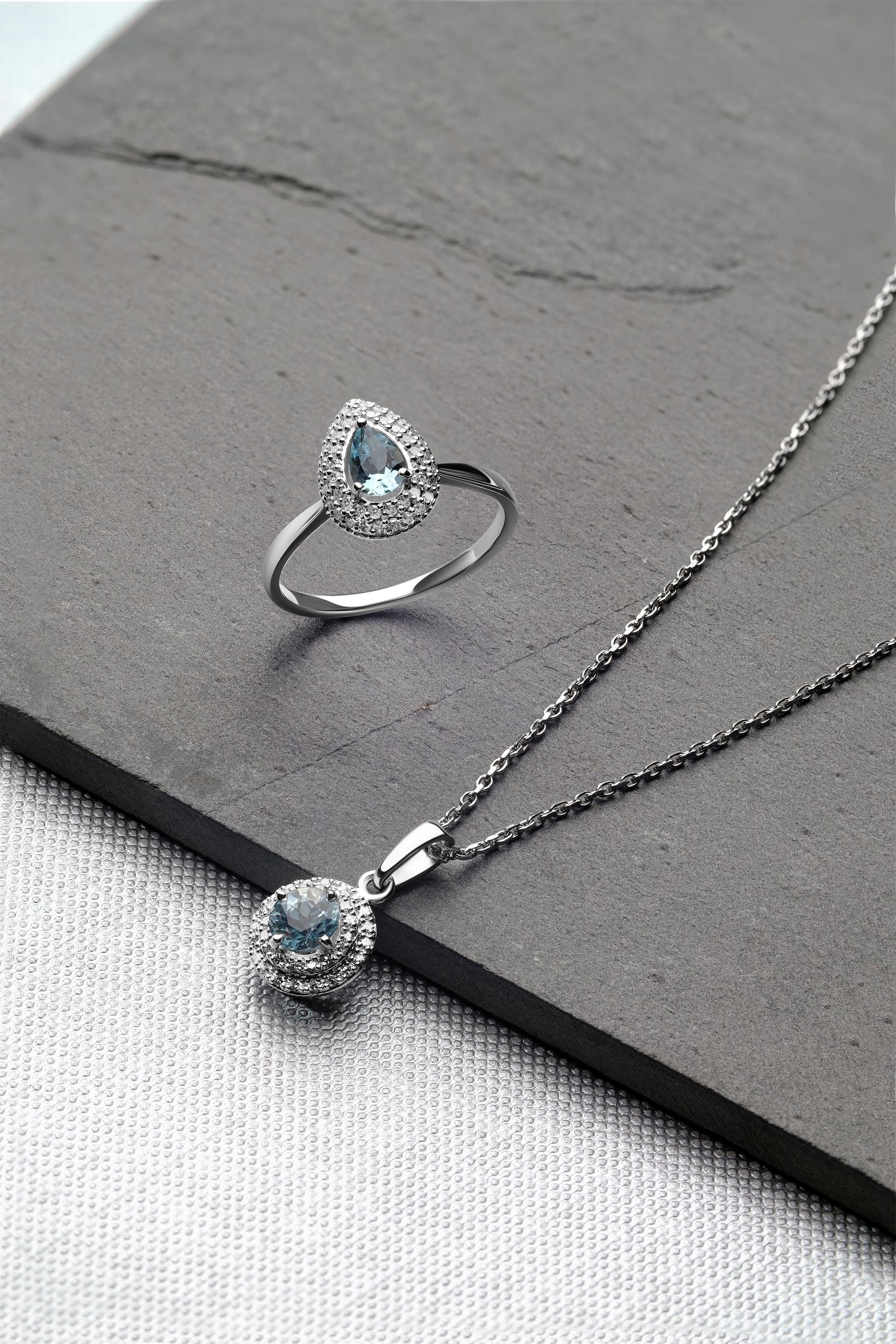 A close up of a necklace and ring on a table.
