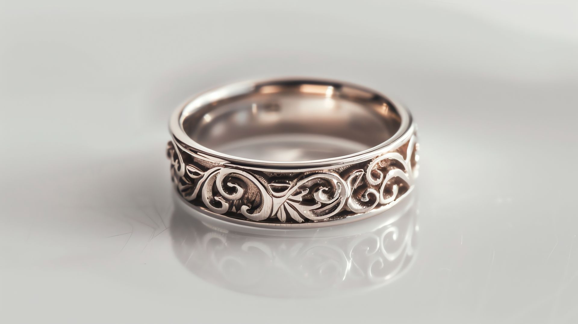 Ornate silver ring with swirling filigree on a white reflective surface