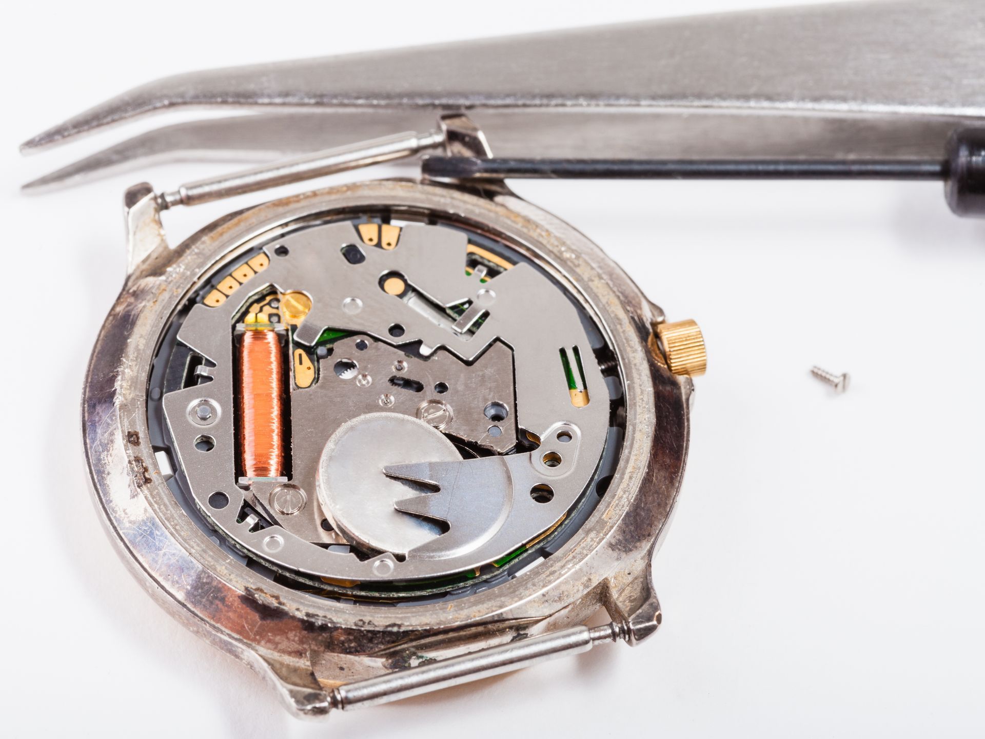 Close-up of an opened wristwatch with exposed inner mechanism and tweezers above it