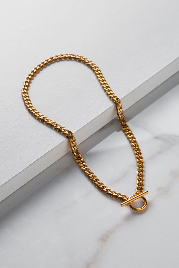 Gold chain necklace with a toggle clasp on a white tabletop