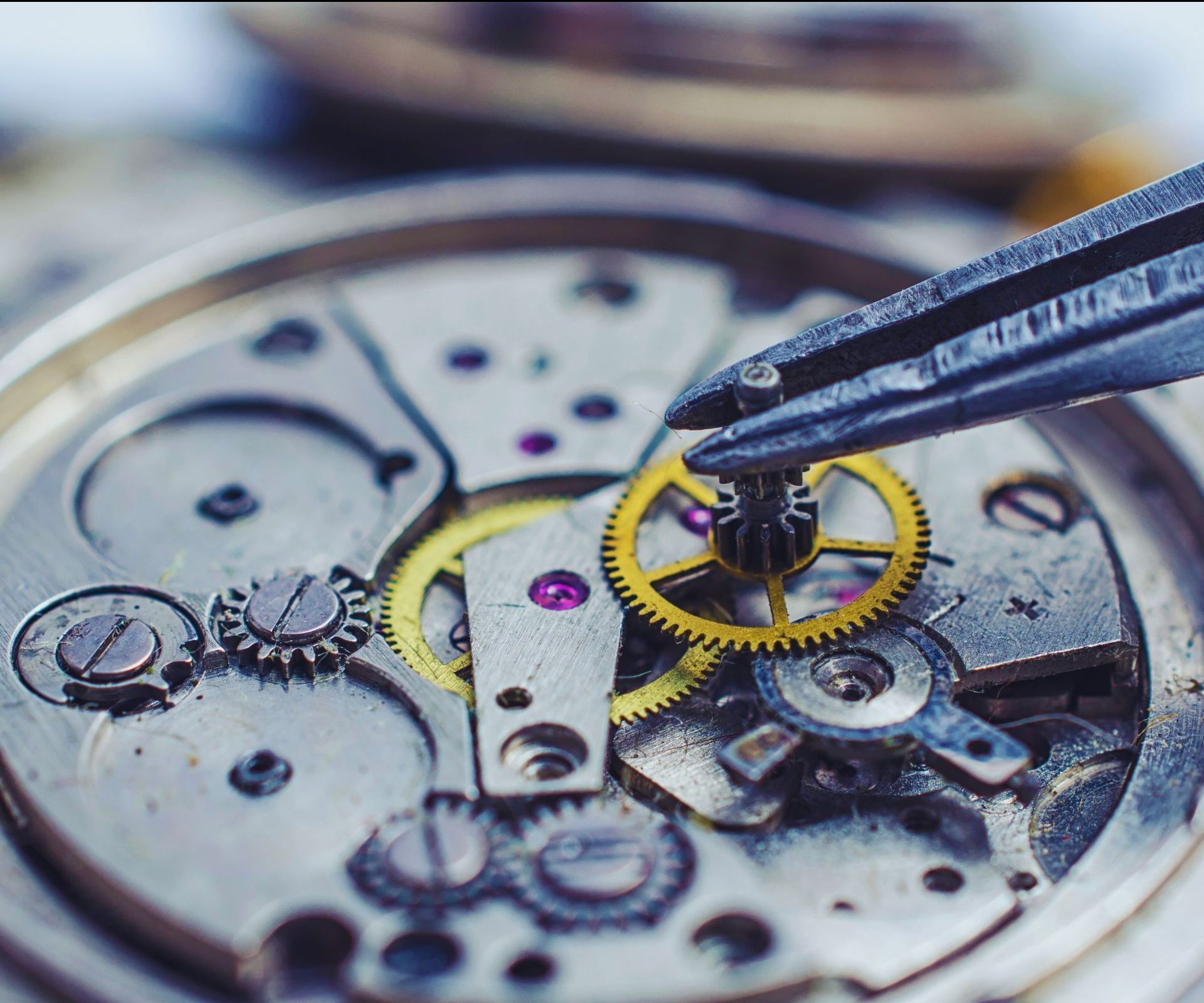 A close up of a watch mechanism with a pair of pliers