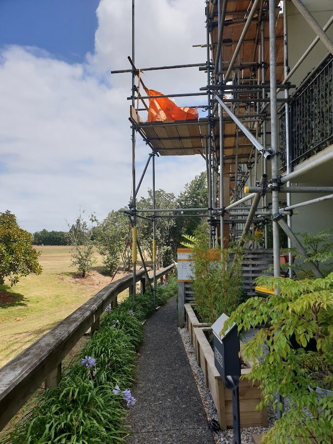 Building exterior scaffolding with orange safety flag against a blue sky