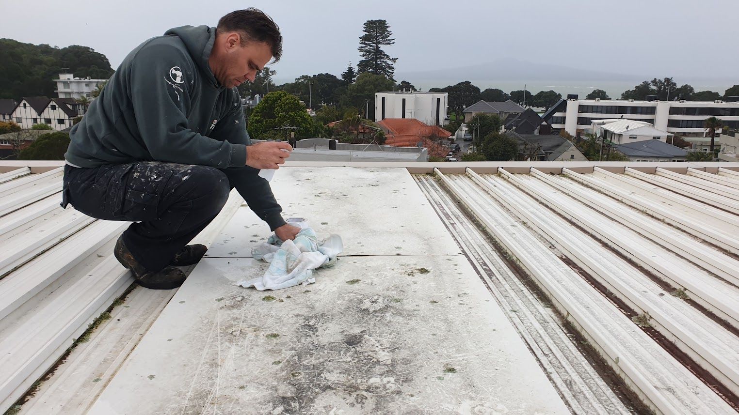Man kneeling on a roof applying sealant