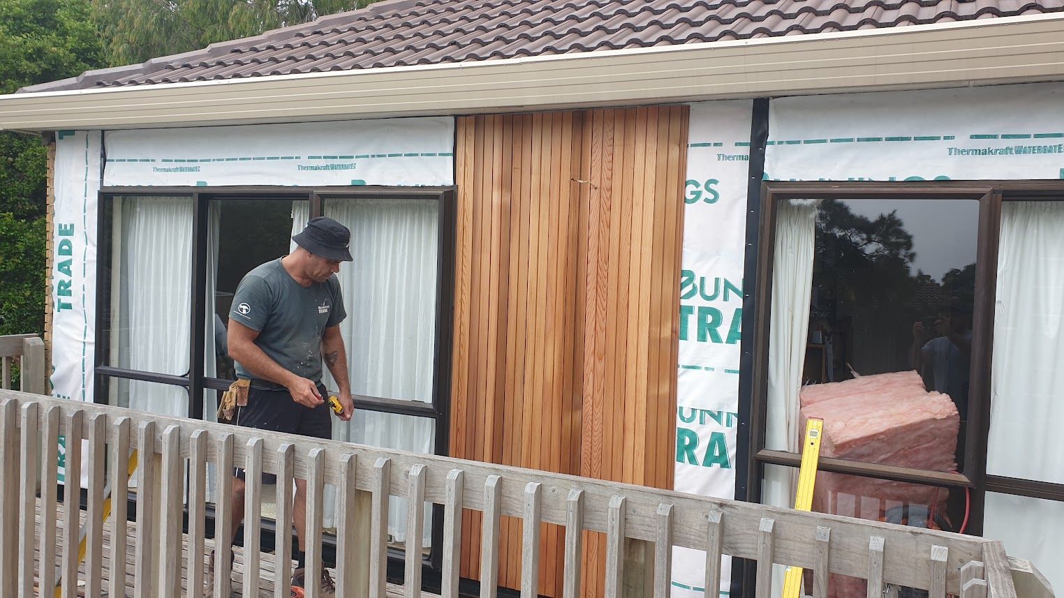 Man installing timber cladding on a house exterior