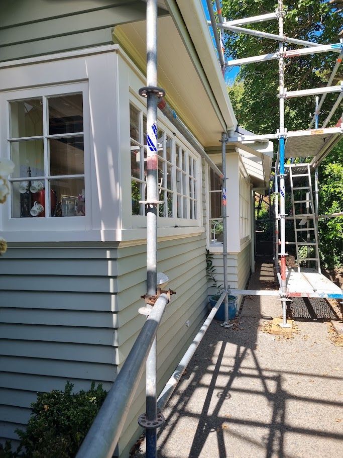 House eave and downpipe with scaffolding among trees