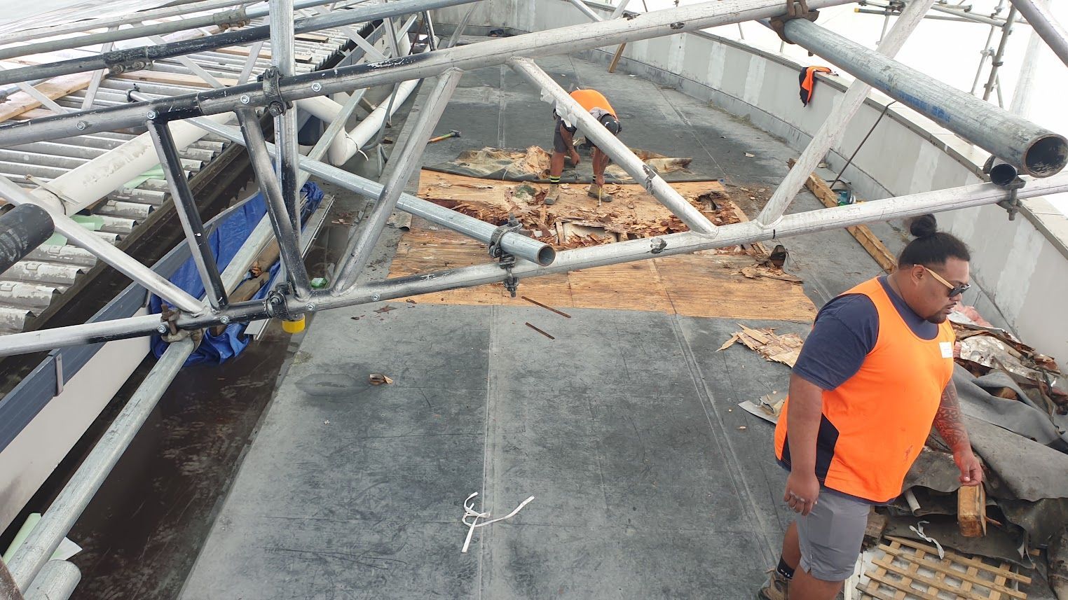 Construction worker in high-vis vest on steel roof framing