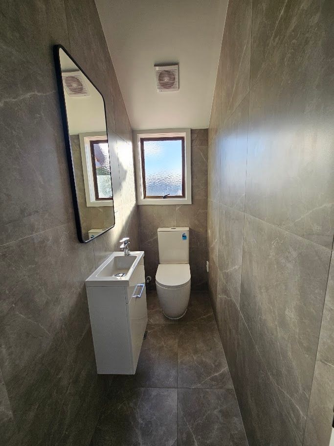 Dark stone-tiled bathroom with wall mirror