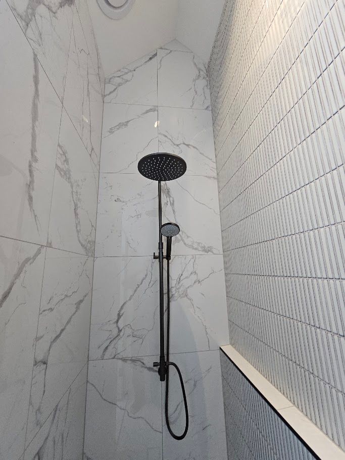 Marble-tiled shower with round rain shower head
