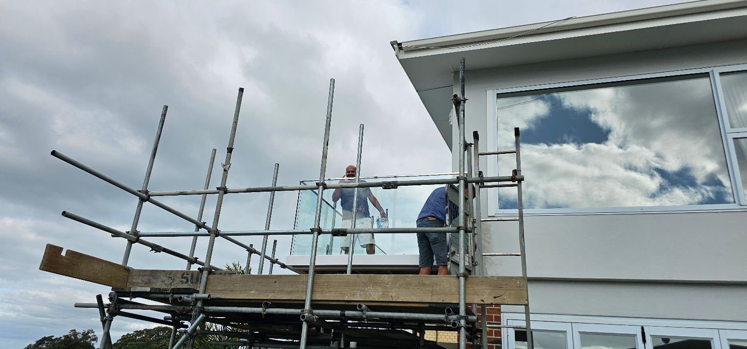Scaffolding beside a modern white house under a cloudy sky