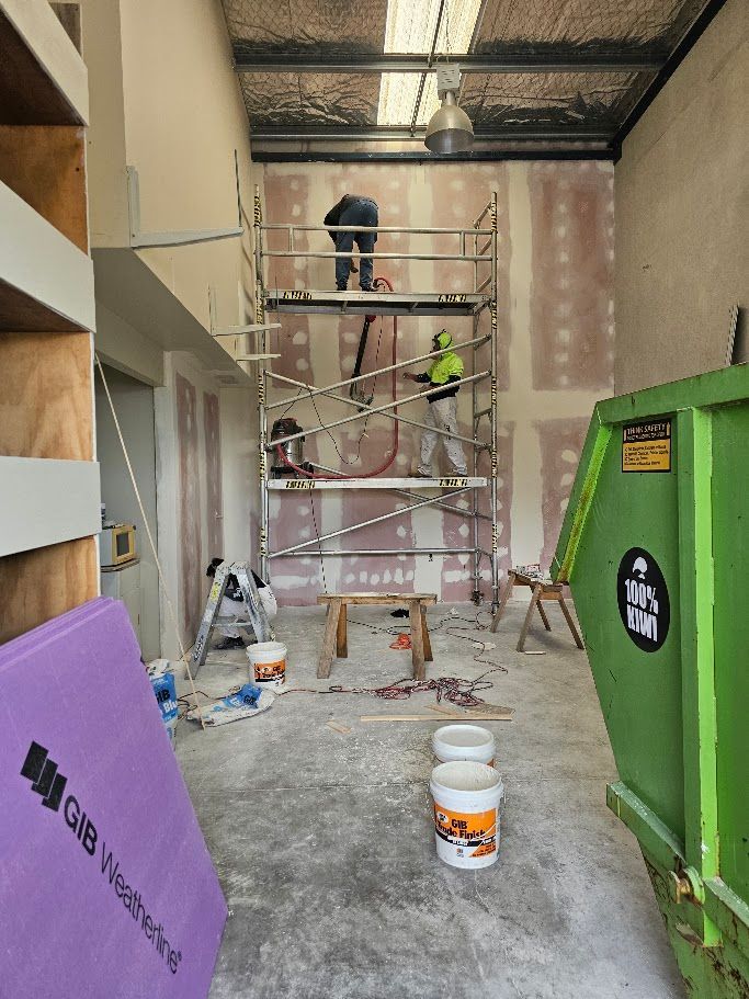 Person working on scaffolding indoors near insulated ceiling