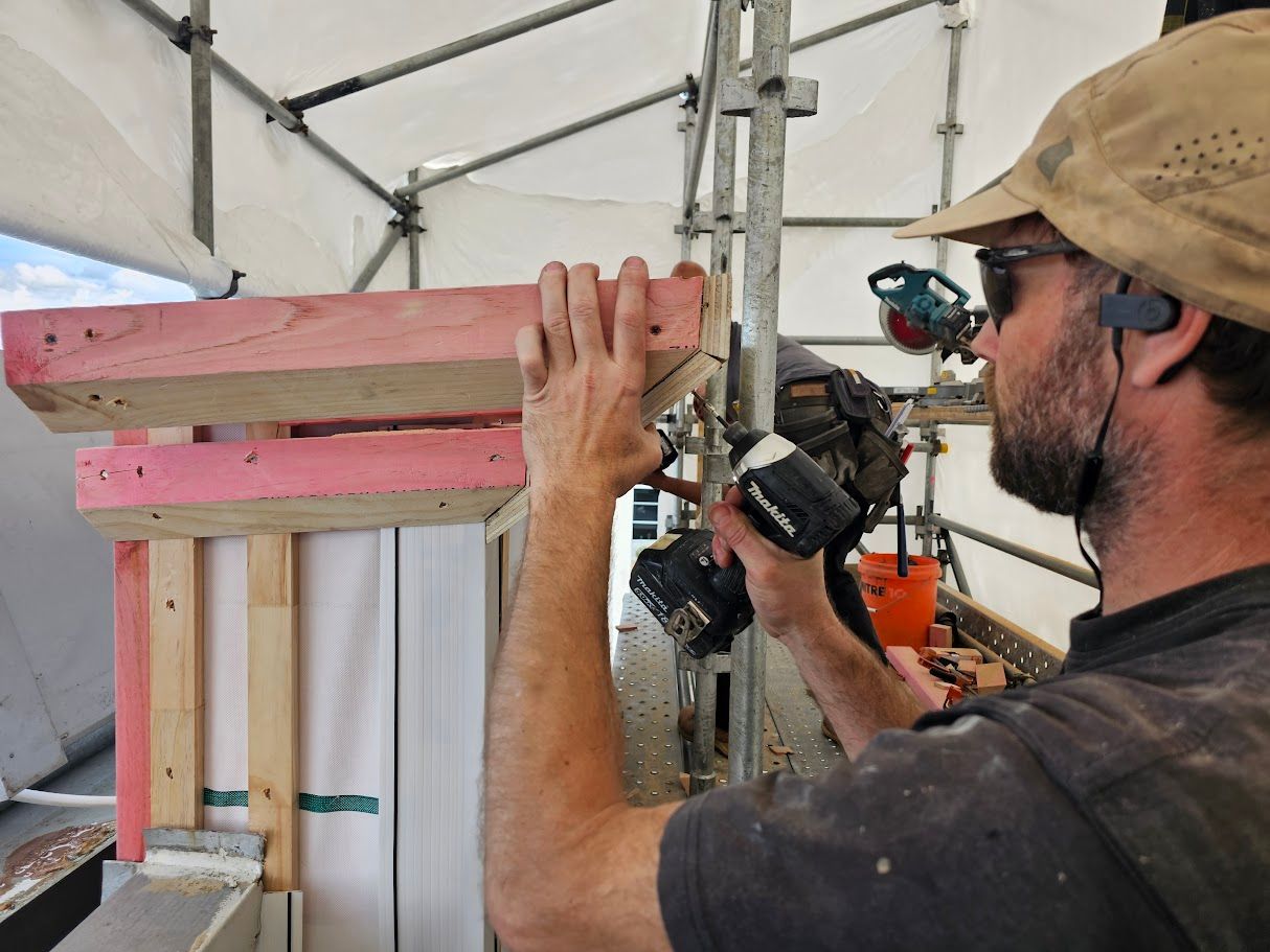 Man using a power tool on a beam with scaffolding