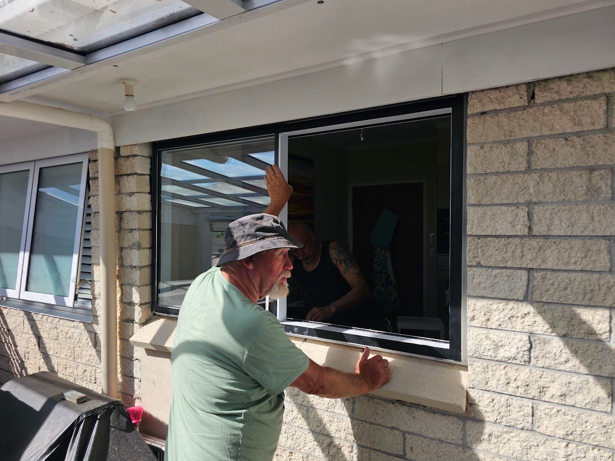 Hand installing a sliding glass door on a brick house