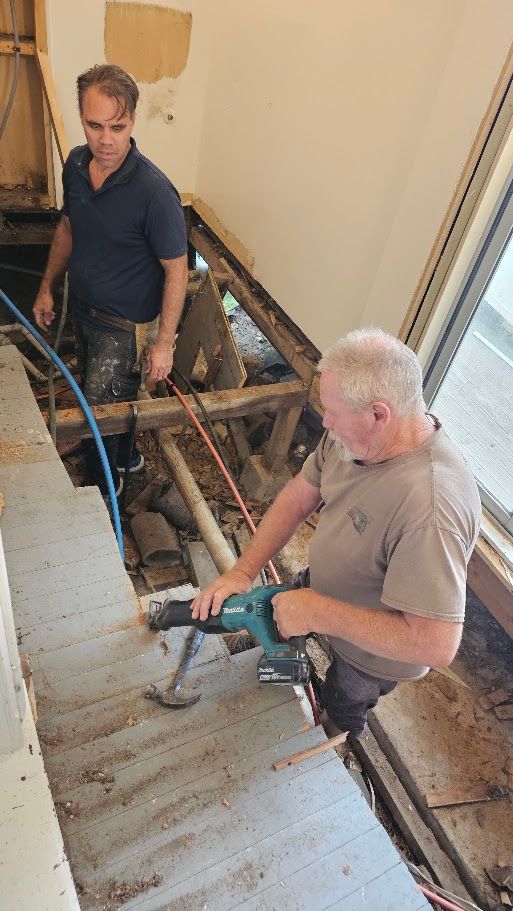 Man standing indoors near a wall patch during renovation