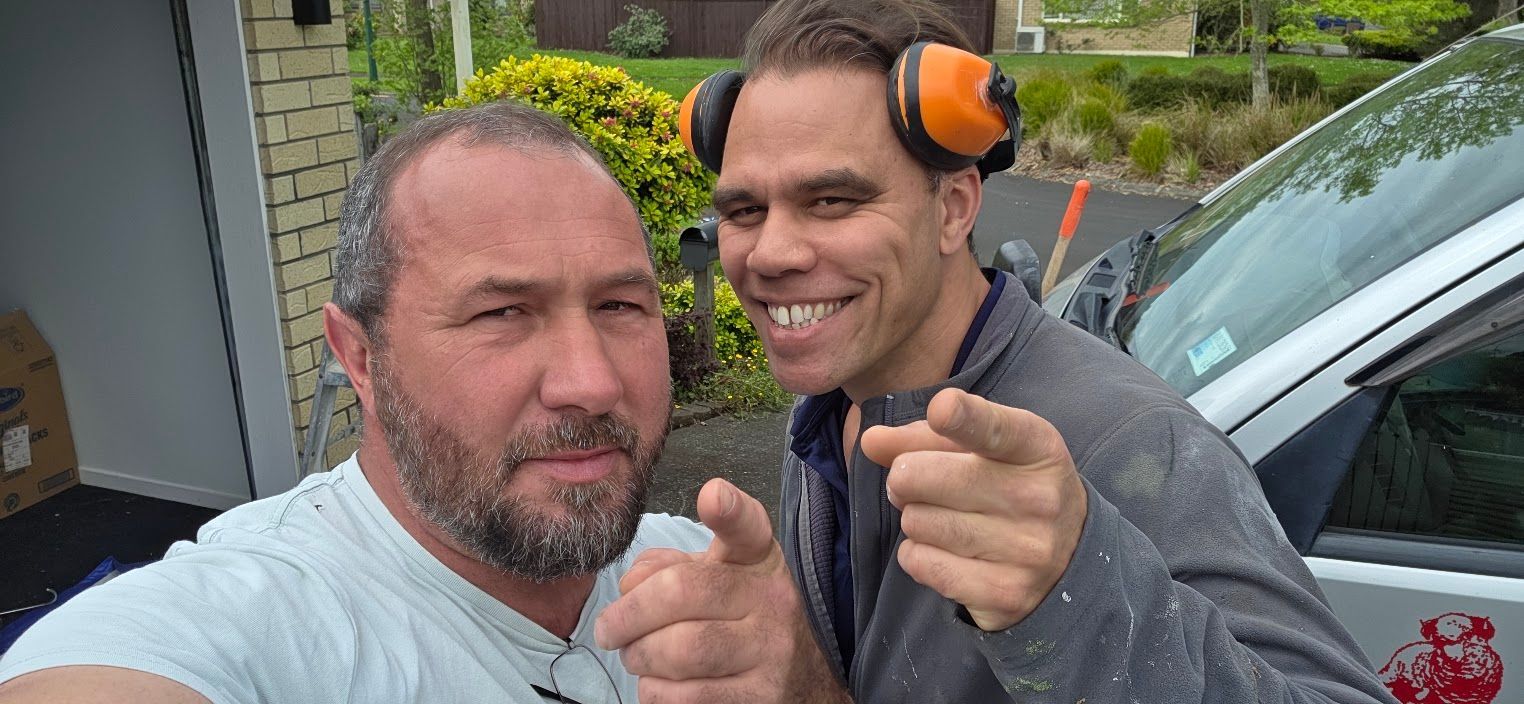 Two men outdoors, one wearing orange ear protection
