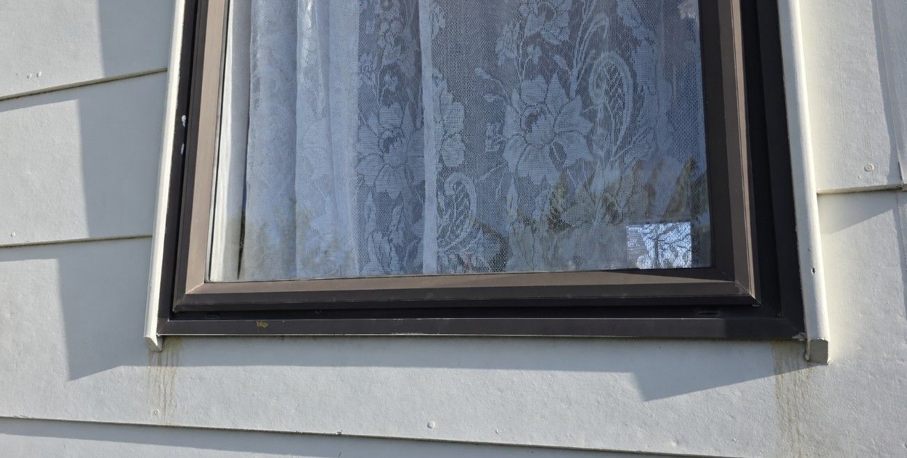 sill corner with grey water staining running down weatherboard cladding